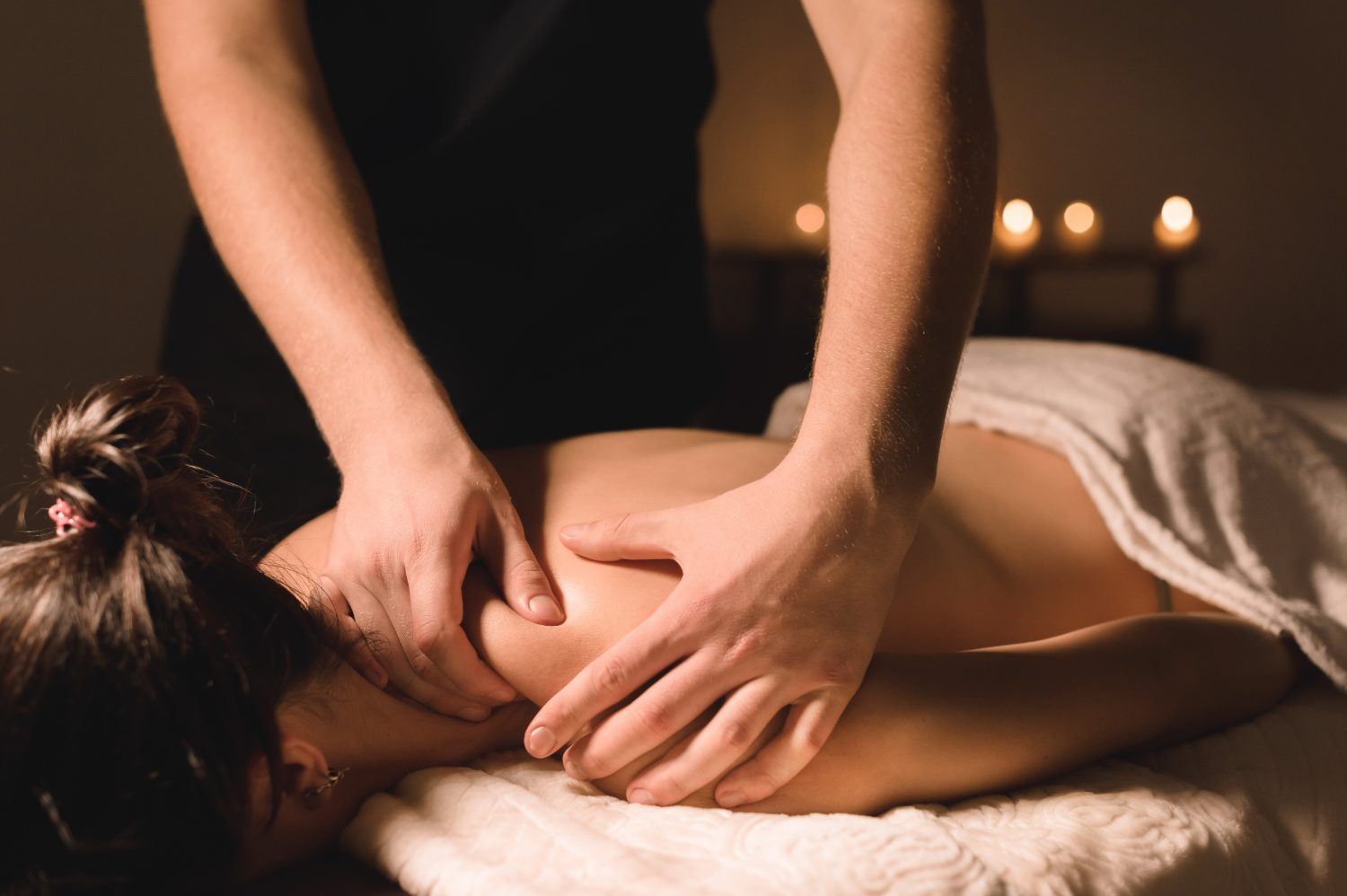 Professional massage therapist performing deep tissue massage on client's back