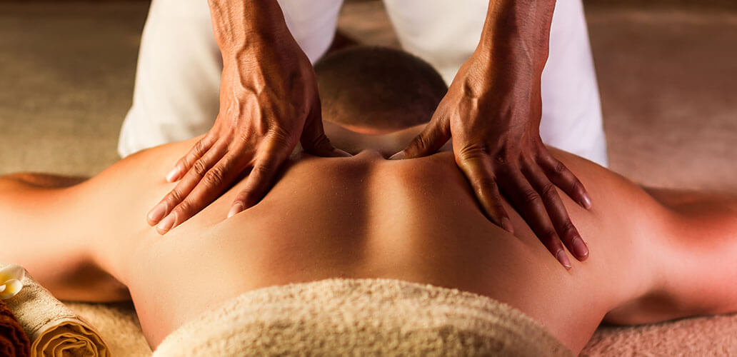Professional massage therapist performing back massage on client