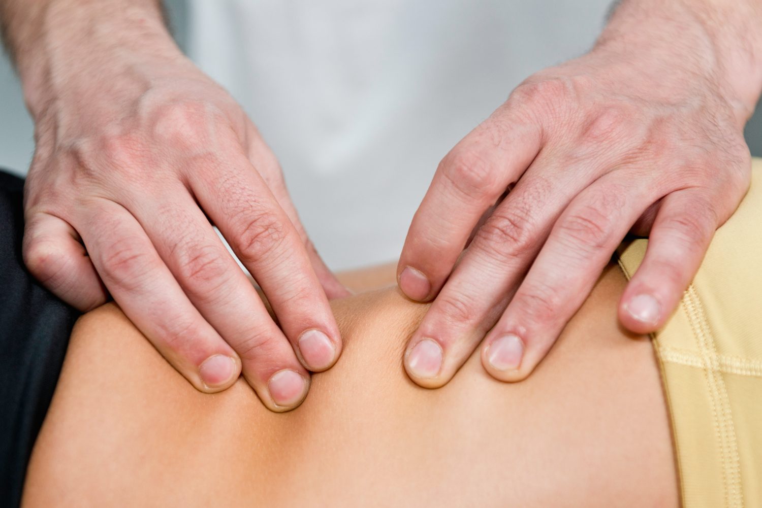 Hands performing massage or physical therapy on a patient's back