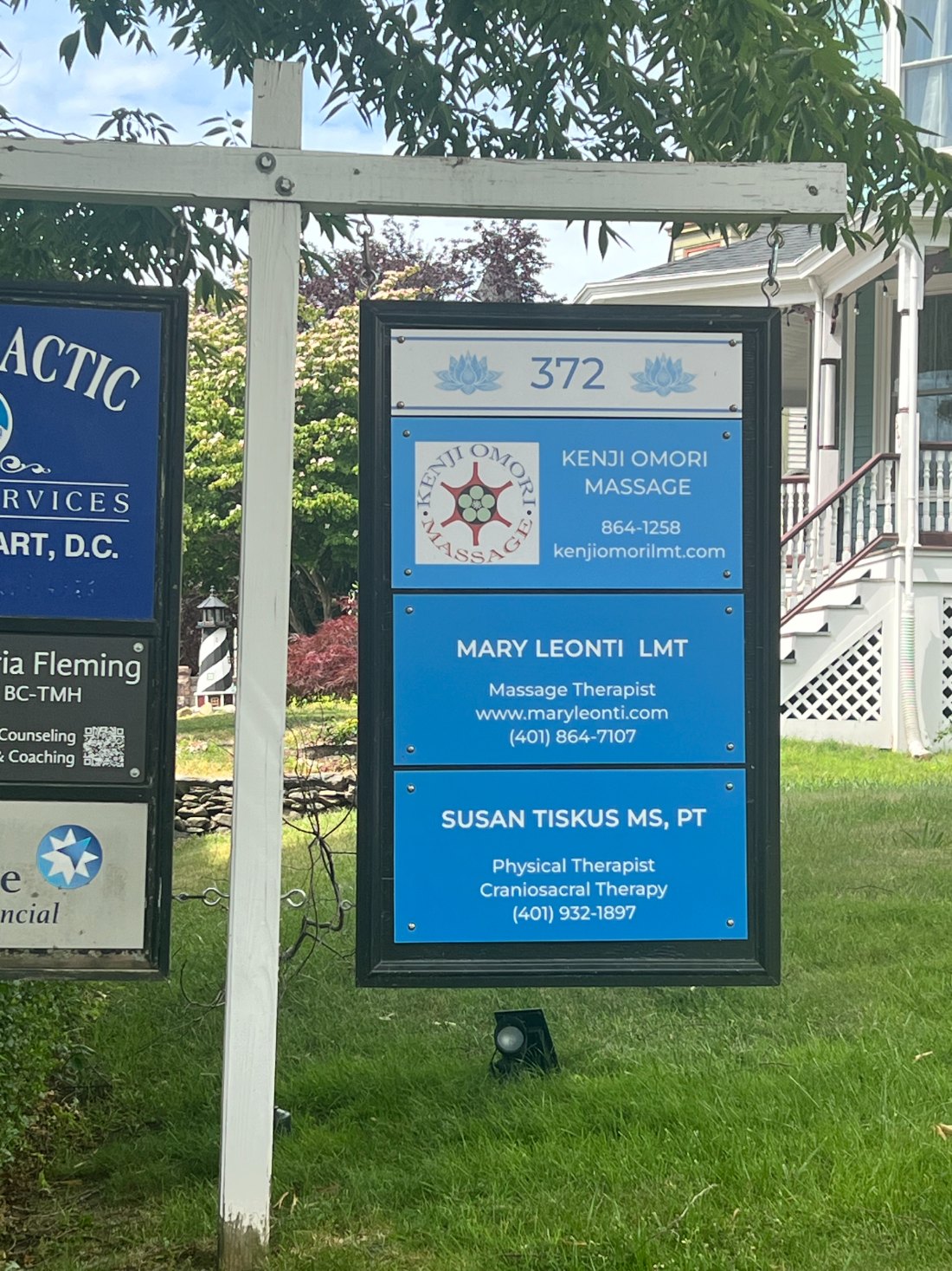 Business directory sign at 372 displaying Kenji Omori Massage, Mary Leonti LMT, and Susan Tiskus PT contact information