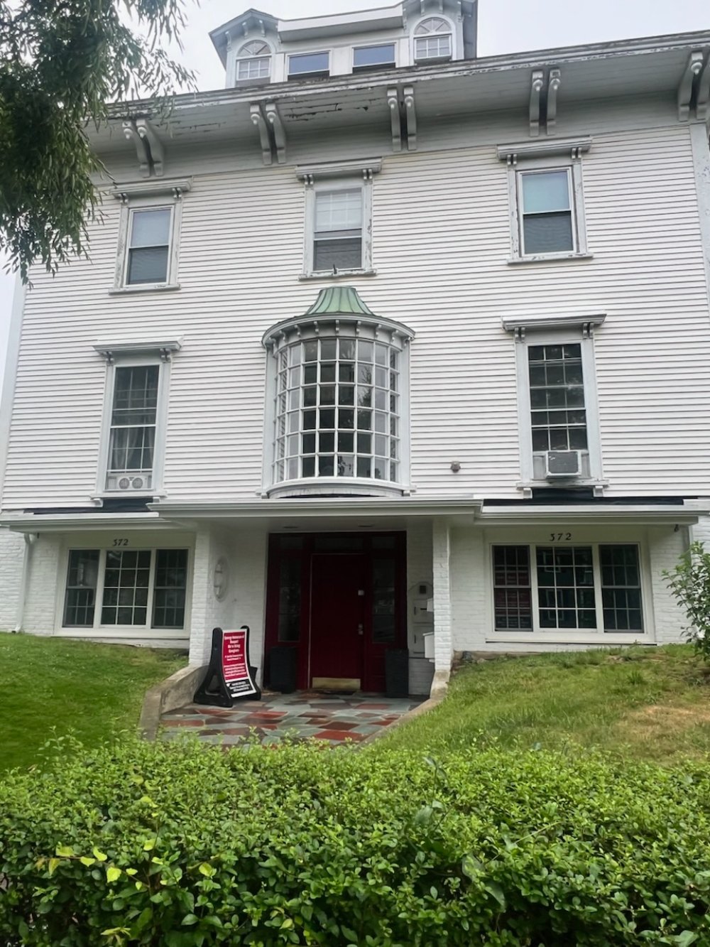 White historic building with green-roofed cupola and curved bay window at 372